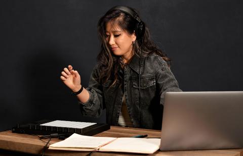 Berklee Online student stands near laptop and open notebook