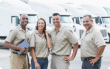 A group of men and women truck drivers at Standard Logistics standing in front of fleet of trucks